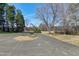 Long asphalt driveway in front of a home bordered by grass and mature trees at 8604 N Roxboro St, Bahama, NC 27503