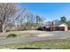 Quaint brick home boasting a circular driveway, attached carport, and a serene, tree-lined property overlooking a field at 8604 N Roxboro St, Bahama, NC 27503