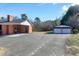 View of the backyard with a brick home, covered parking, and a detached garage at 8604 N Roxboro St, Bahama, NC 27503