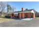 Classic brick home featuring an attached carport, surrounded by mature trees and a well-maintained lawn and long driveway at 8604 N Roxboro St, Bahama, NC 27503