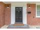 Charming brick home featuring a classic black front door with decorative trim and stylish outdoor lighting at 938 Hargrove St, Henderson, NC 27536