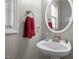 Charming half bath featuring a pedestal sink, oval mirror, and a window at 1006 Scotsburg Trl, Hillsborough, NC 27278