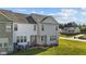 View of a townhome back exterior with lawns, grill, and AC units on green grass near other homes at 101 Wimbledon Ct, Clayton, NC 27520