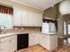 Charming kitchen with white cabinets, neutral countertops, and a window with red striped valances at 103 Glenstone Ln, Cary, NC 27518