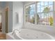 Bright bathroom featuring a large soaking tub set against a backdrop of a large window with beautiful views at 109 Chimeneas Pl, Chapel Hill, NC 27517