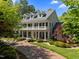 Beautifully landscaped home featuring a brick driveway, large porch, and dormer windows, surrounded by mature trees at 109 Chimeneas Pl, Chapel Hill, NC 27517