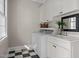 Well-lit laundry room with white cabinets, front load washer, and black and white checkered flooring at 109 Chimeneas Pl, Chapel Hill, NC 27517