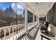 Long, covered porch with white columns and ceiling fans provides a relaxing outdoor space with scenic nature views at 109 Chimeneas Pl, Chapel Hill, NC 27517