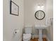 Stylish powder room with pedestal sink, round mirror, and modern fixtures at 109 Chimeneas Pl, Chapel Hill, NC 27517