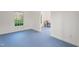 Bright, open room with blue floors, featuring a window and doorway to a separate area with utilities at 109 Chimeneas Pl, Chapel Hill, NC 27517