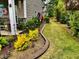 Well-maintained front yard with a colorful garden and a decorative wind spinner along a neatly edged lawn at 110 Gulley Glen Dr, Garner, NC 27529