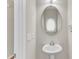 Bright powder room featuring a pedestal sink, decorative oval mirror, and modern fixtures at 110 Gulley Glen Dr, Garner, NC 27529