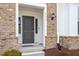 Inviting entryway with a gray front door, brick facade, and stylish outdoor lighting at 111 Hickory Plains Rd, Knightdale, NC 27545