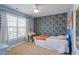 Comfortable bedroom with blue walls, wallpaper, a twin bed and large windows with white curtains at 11342 Oakcroft Dr, Raleigh, NC 27614