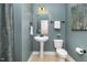 Charming powder room featuring a pedestal sink, floral art, and sleek fixtures at 121 Stone Nut Trl, Fuquay Varina, NC 27526