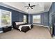 Stylish bedroom with tray ceiling, three windows, wood accent wall, and neutral carpeting at 121 Stone Nut Trl, Fuquay Varina, NC 27526