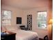 A bedroom with carpeted floors, two windows, an ornate wall hanging, desk, and a bed with white sheets at 1704 Delaware Ave, Durham, NC 27705