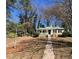 Charming home with inviting front porch, black shutters, and surrounded by mature trees and greenery at 1704 Delaware Ave, Durham, NC 27705