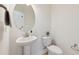 Bright powder room featuring a pedestal sink with modern fixtures and neutral wall color, with a modern round mirror at 1913 Brodgen Ln, Durham, NC 27703