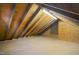 Large attic featuring wooden beams, flooring, and a small window, perfect for storage or future expansion possibilities at 2005 Glenwood Ave, Raleigh, NC 27608