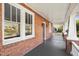 Spacious front porch with brick facade, white railings, and a gray wood floor, perfect for relaxing outdoors at 2005 Glenwood Ave, Raleigh, NC 27608