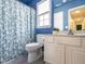 Bright blue bathroom with white cabinets, blue patterned shower curtain, and natural light at 206 May Farm Rd, Pittsboro, NC 27312