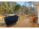 Enjoy outdoor cooking on this wood deck with a grill, rocking chairs, and wood railing, surrounded by trees at 2204 Gentry Dr, Durham, NC 27705