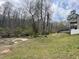 A mostly clear backyard with a small ravine surrounded by a dense tree line and a cloudy sky at 274 Roaring Creek Dr, Garner, NC 27529