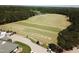 Aerial view of a driving range with golf carts parked nearby, backed by mature trees and a picturesque pond at 297 Colonial Ridge Dr, Pittsboro, NC 27312
