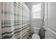 Well-lit bathroom features neutral shower curtain, window, toilet, and light gray walls at 3805 Barberry Lake Ct, Fuquay Varina, NC 27526