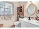 Quaint bathroom with vintage cabinet, tiled floors, and oval mirror at 3836 Gloucester Rd, Rocky Mount, NC 27803