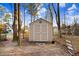 Backyard shed has double doors and window, with pool in the distance beyond the trees at 3836 Gloucester Rd, Rocky Mount, NC 27803