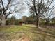A large backyard with lush trees and a storage shed sits on a grassy lawn at 4 Second St, Franklinton, NC 27525