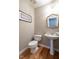 Neat half bathroom featuring hardwood floors, pedestal sink, and a modern mirror with simple decor at 426 Fincastle Dr, Cary, NC 27513