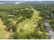 Aerial view of verdant golf course with sand traps and lake, surrounded by dense woods and luxury homes at 498 Mountain Laurel, Chapel Hill, NC 27517
