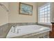 Relaxing soaking tub featuring tile surround, window, and an elegant faucet at 498 Mountain Laurel, Chapel Hill, NC 27517