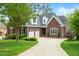 Traditional brick home with a three-car garage, well-manicured lawn, and mature trees at 498 Mountain Laurel, Chapel Hill, NC 27517