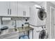 Bright laundry room features stacked washer and dryer and gray cabinets with black hardware at 520 Log Barn Rd, Pittsboro, NC 27312
