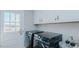 Modern laundry room with washer, dryer, white cabinetry, hardwood floors, and outdoor access at 5436 New Oak Trl, Burlington, NC 27217