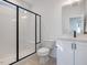 Modern bathroom featuring a glass-enclosed shower, a toilet, and vanity with sleek fixtures and bright white tiles at 705 Vine Pkwy, Pittsboro, NC 27312