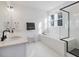 Modern bathroom with a walk-in shower, a soaking tub under a bright window, and dual sinks at 705 Vine Pkwy, Pittsboro, NC 27312