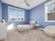 Cozy blue bedroom with large windows offering neighborhood views, carpet flooring, and a ceiling fan at 705 Vine Pkwy, Pittsboro, NC 27312