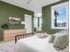 Stylish primary bedroom boasts a comfortable bed, green walls, and a peaceful view from its bright windows at 705 Vine Pkwy, Pittsboro, NC 27312