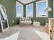 Sitting room with a comfy round chair, ottoman, mirror, neutral carpet, natural light, and soft green walls at 705 Vine Pkwy, Pittsboro, NC 27312