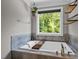 Bright bathroom featuring a soaking tub with scenic outdoor views and stone accents at 766 Horizon Dr, Pittsboro, NC 27312