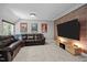 Cozy living room featuring a leather sofa, exposed brick wall, and a wall mounted television at 766 Horizon Dr, Pittsboro, NC 27312