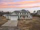 Traditional two-story home featuring an attached two-car garage and covered porch at sunset at 7880 Flower Hill Rd, Middlesex, NC 27557