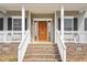 Inviting front porch with brick steps, white railings, and a beautifully crafted wooden front door at 7880 Flower Hill Rd, Middlesex, NC 27557
