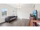 Bright living room featuring a dark leather sofa, TV, wood flooring, and natural light from two windows at 7880 Flower Hill Rd, Middlesex, NC 27557