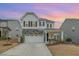 Charming two-story home with stone accents, a covered porch bathed in the glow of sunset at 824 Wrights Creek Way, Wake Forest, NC 27587